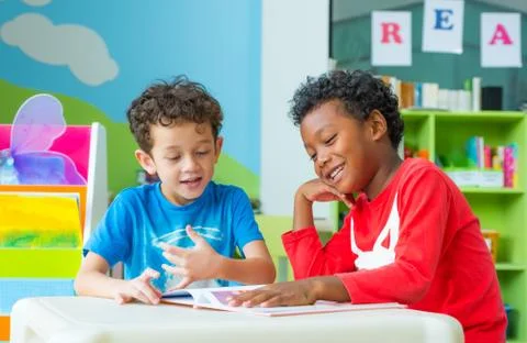Two boy kid sit on table and reading tale book  in preschool library,Kinderga Stock Photos