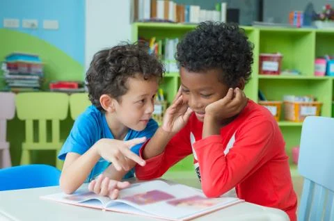 Two boy kid sit on table and coloring in book  in preschool library,Kindergar Stock Photos