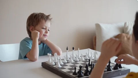 Two boy playing chess in light room. Two brothers playing chess. Stockbeeldmateriaal 105090438