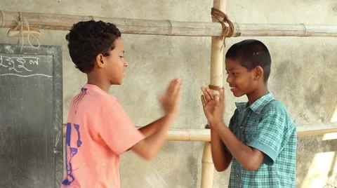 Two boy students play a clapping game in a village school in Bengal, India Stock Footage 65789802