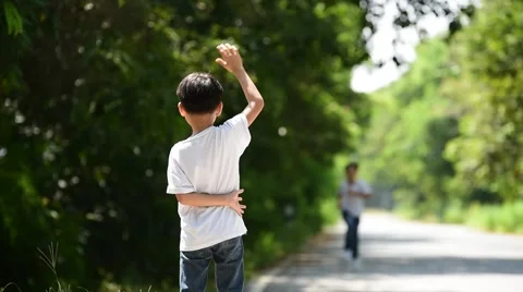 Two boy walk and run and wave their hand to meet each other on the urban road an Stock Footage 68989697