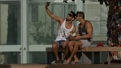 Two Boyfriend Boys are Taking A Selfie Sitting On A Bench With A Dog Stock Footage 90378417