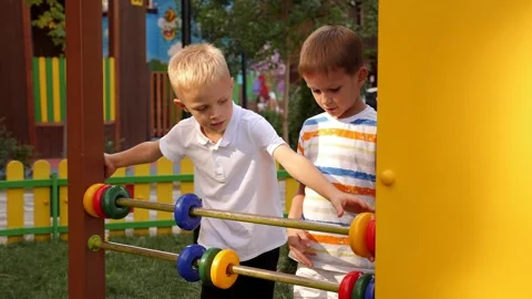 Two boys are learning to count on large plastic accounts on the playground. Video stock 219206228