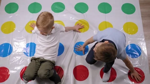 Two boys are playing an active twister game at home in the living room. Stock Footage 329277426