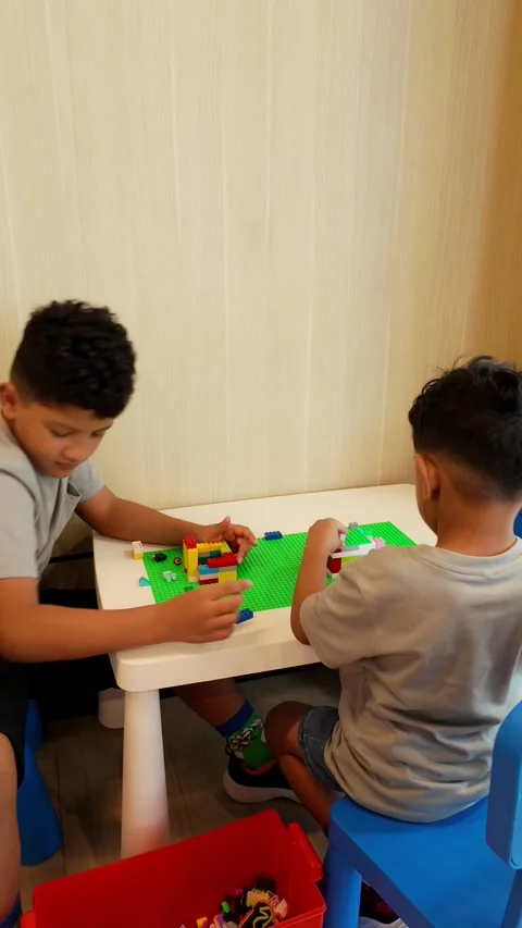 Two boys are playing with legos at a table Stock Footage 328774866