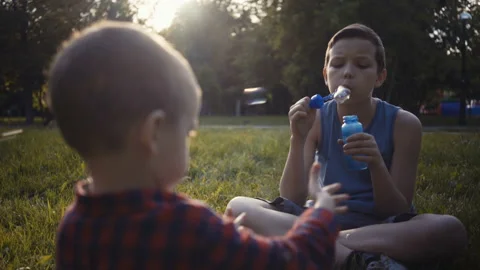 Two boys blowing soap bubbles outdoors summer. Vídeo Stock 91078756