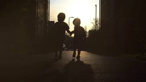 Two boys , brothers walking towards sun and holding hands Stock Footage 80238109