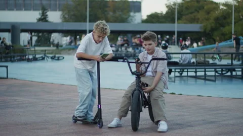 Two Boys Browsing Smartphones in Skate Park Stock Footage 346156811