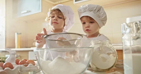 Two boys in chef hats having fun mixing flour in a bowl Stock Footage 266501582