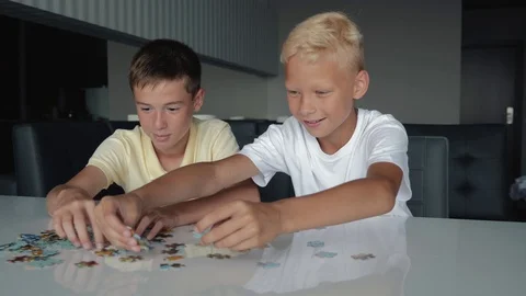 Two boys collect puzzles. Teamwork. Way to success. Happy family is engaged in Video stock 121529054