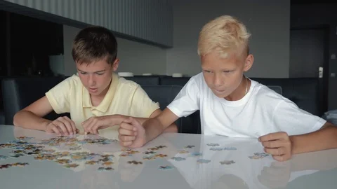 Two boys collect puzzles. Teamwork. Way to success. Happy family is engaged in Stock Footage 122688415