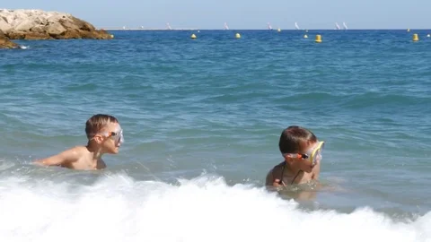 Two boys in diving mask having fun in sea waves - 4K Stock Footage 80233107