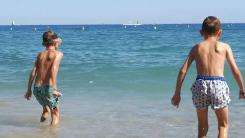 Two boys in diving mask jumping in sea waves - 4K Stock Footage 80232357