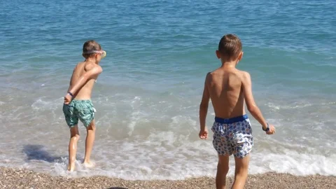 Two boys in diving mask running to the sea and splashing in water - 4K Stock Footage 80232175