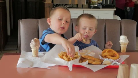 Two boys eating a deep fried fast food meal.  Video stock 76609568