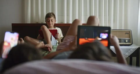 Two boys engaging in different activities on a bed during leisure time Stock Footage 273033071
