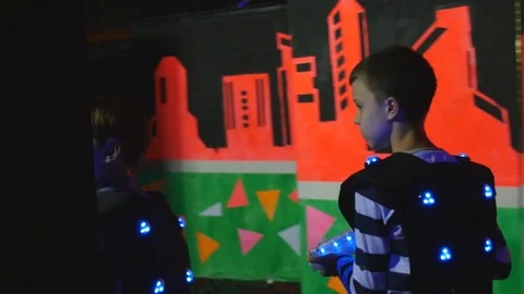 Two boys in the equipment for playing laser tag walk through the labyrinth Stock Footage 77357364