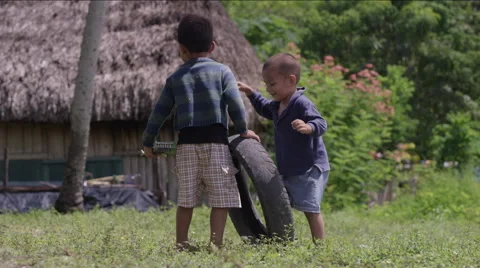 Two boys fighting for a tire while playing outside a hut in village, Guatemala Stock Footage 63053652