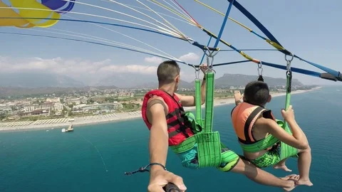 Two boys go parasailing after a motorboat pulling them over a sea coast 動画素材 84132599