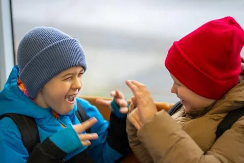 Two boys have fun while traveling in public transport near the window Foto stock
