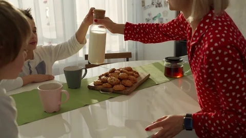 Two boys having breakfast in modern kitchen. Boy eat cookie with milk. White Vídeos de archivo 103685199