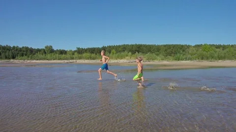 Two boys having fun running on sand beach Stock Footage 114789950