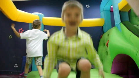 Two boys jump at inflatable playground Stock Footage 37554566