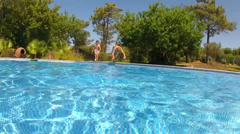 Two Boys Jumping Into Pool Then Swims Underwater To Camera Stock Footage