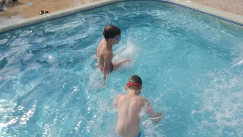 Two boys jumping swimming pool jump water kids swimming boy water fun summer Stock Footage 241398949