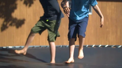 Two Boys Jumping on a Trampoline in Slow Motion and Nearly Colliding Stock Footage 94876509