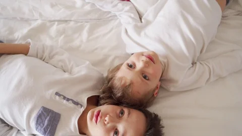 Two boys lie in bed, talking and looking at the ceiling Stock Footage 105092068