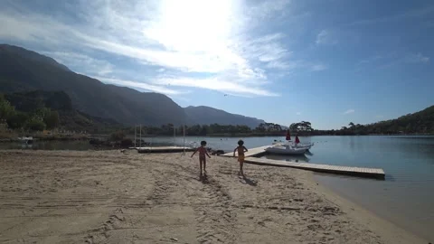 Two boys on the lonely beach head to the water cycles Vidéo 142065961