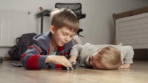 Two boys lying on floor and having a fight with toys. Children playing alone, de Vidéo 238557457