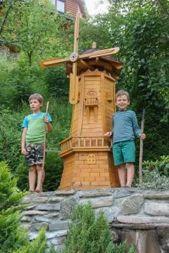 Two boys next to small mill in summer city park Stock Photos