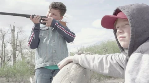 Two boys outside shooting a bb gun sharing it with eachother. Video stock 169734422
