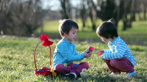 Two boys in the park, having fun with colored eggs for Easter, springtime Stock Footage 47568412