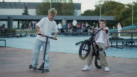 Two Boys Performing BMX Bicycle and Scooter Tricks in Skate Park Video stock 346156712