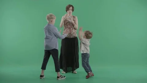 Two boys play with soap bubbles which blows their mom Stock Footage 77634764