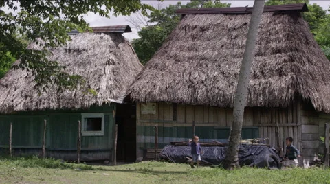 Two boys playing with tire outside a hut in village, Guatemala Stock Footage 63053559