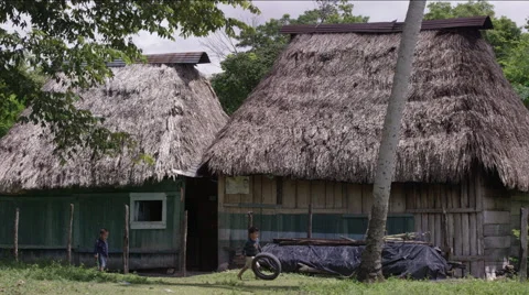 Two boys playing with tire outside a hut in village, Guatemala Stock Footage 63053574
