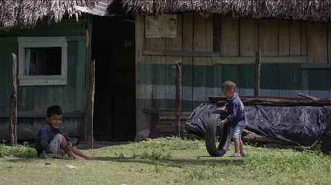 Two boys playing with tire outside a hut in village, Guatemala Stockbeeldmateriaal 63053624