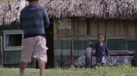 Two boys playing with tire outside a hut in village, Guatemala Stock Footage 63053676