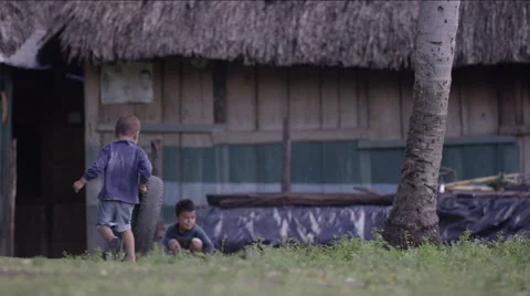 Two boys playing with tire outside a hut in village, Guatemala Stock Footage 63053783