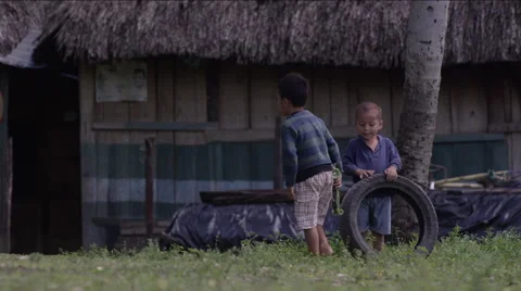 Two boys playing with tire outside a hut in village, Guatemala Stockbeeldmateriaal 63053876