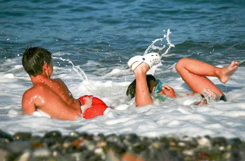 Two boys playing with the waves at the beach Stock Photos