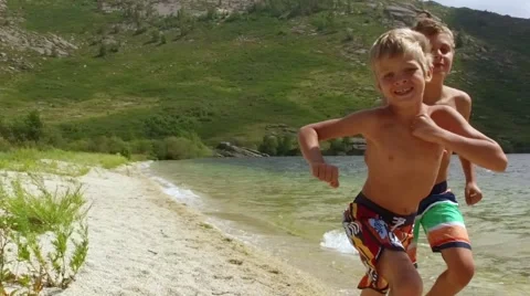 Two boys run a race on the beach in slow motion Stock Footage 68175668