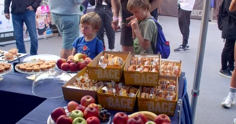 Two boys sampling packed sandwiches and fruit at outdoor schoolgraduat Stock Footage 347965390