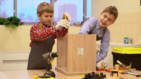 Two boys with screwdrivers and tools repairing wooden stool Stock Footage 71168977