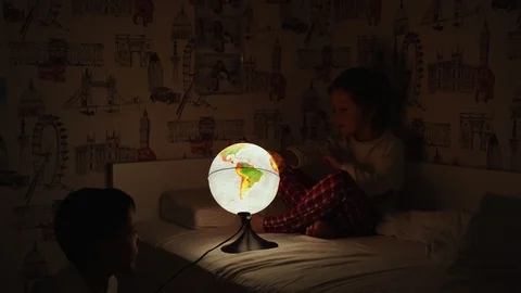 Two boys sitting in bed at night rotating the globe and dreams of traveling. Vidéo 101029569