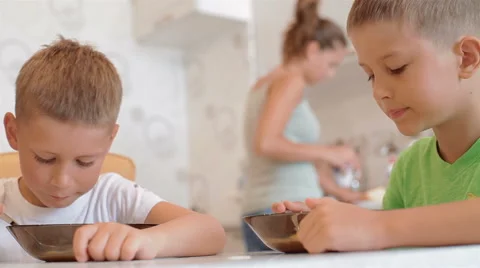 Two boys sitting at the table eating cornflakes with milk Stock Footage 40331784
